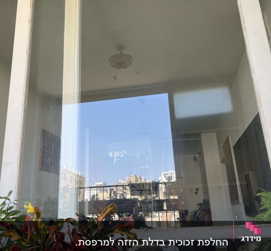 חלון זכוכית גדול עם השתקפות של חדר פנימי